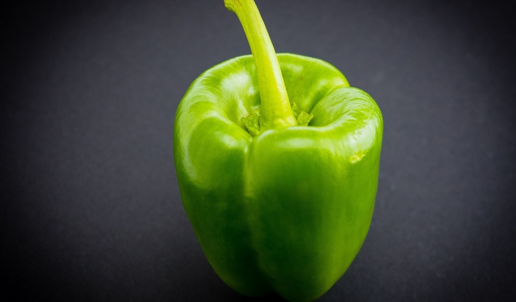 Большой зеленый перец на сером  фоне
