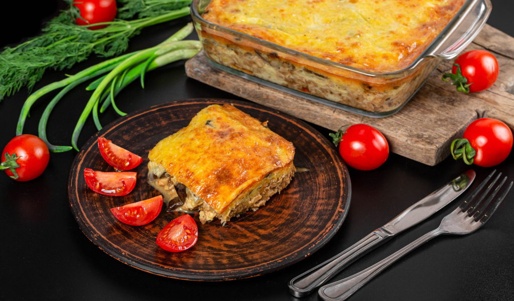 Лазанья на тарелке с помидорами и зеленью
