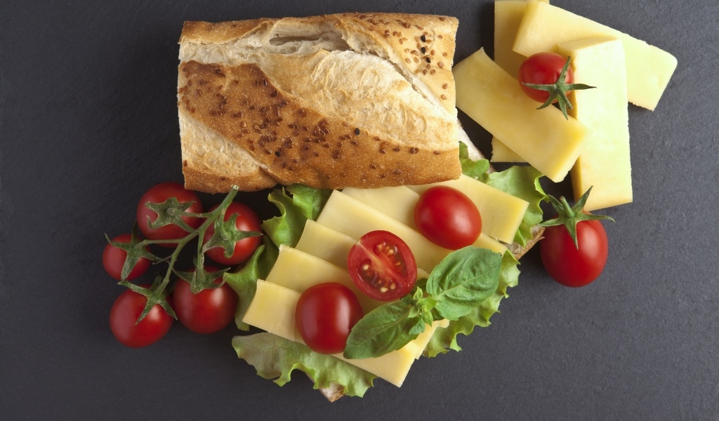 Батон с сыром и помидорами на сером фоне