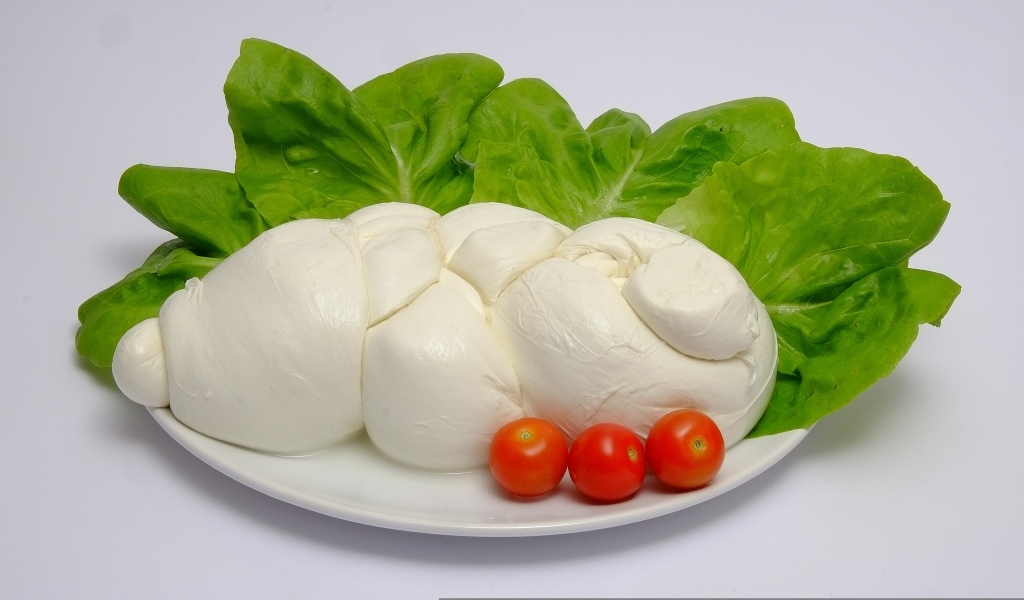 Сыр моцарелла на тарелке с листьями салата и помидорами