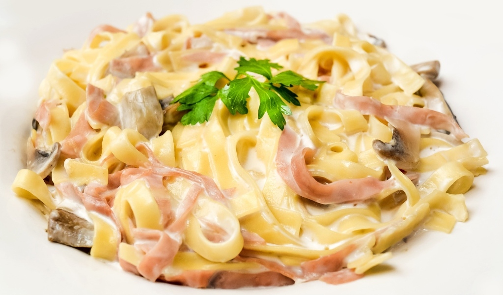 Лапша с беконом и грибами на белом фоне