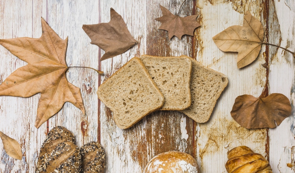 Куски хлеба с листьями на деревянном столе