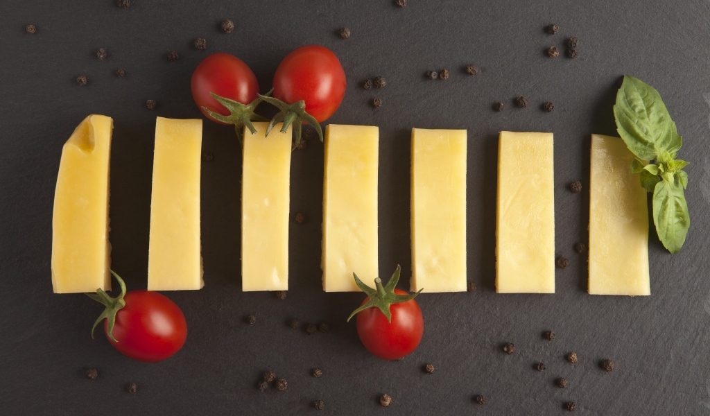Кусочки сыра с помидорами на сером столе