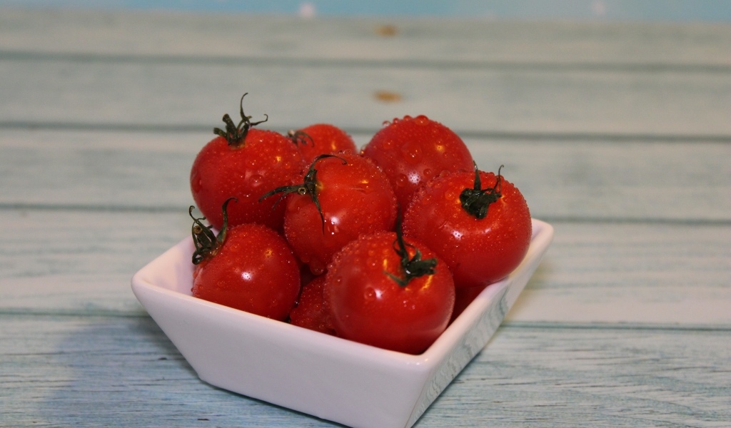 Красные мокрые помидоры в белой тарелке