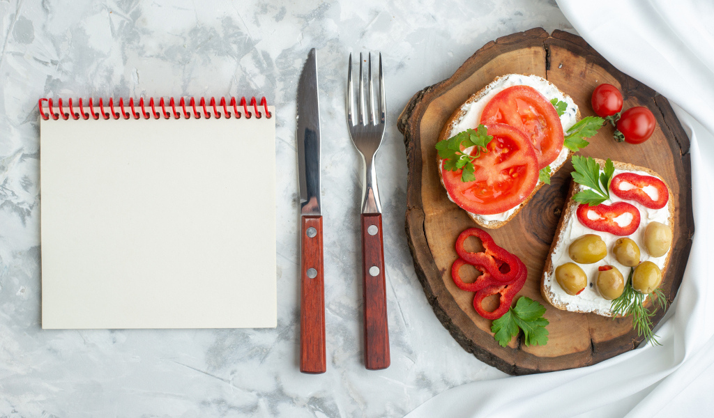 Бутерброды на столе со столовыми приборами и блокнотом