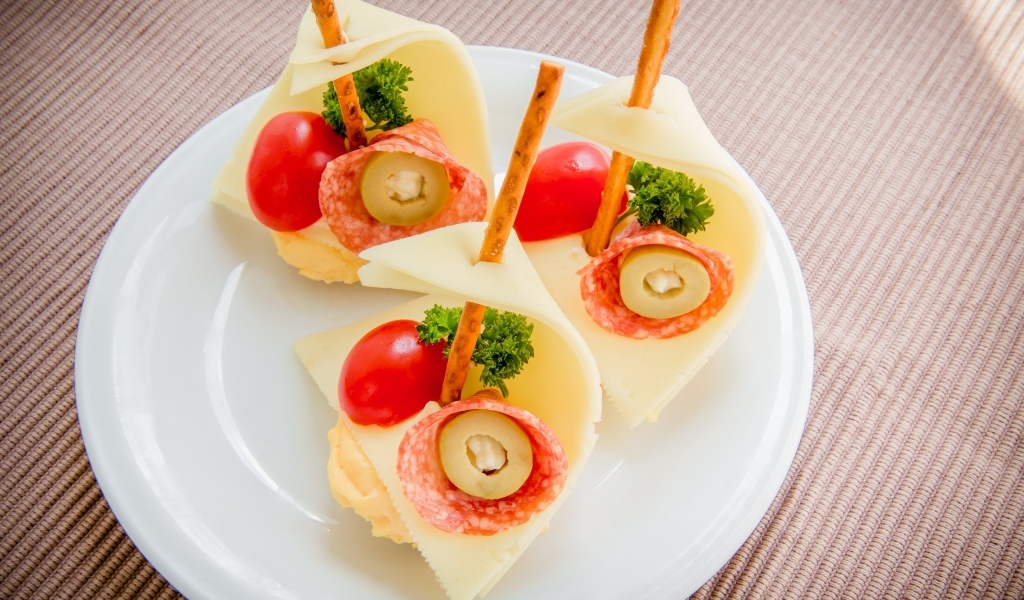 Бутерброды с колбасой, сыром и помидорами на белой тарелке