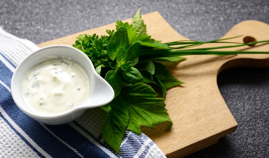 Соус с зеленью на деревянной доске 