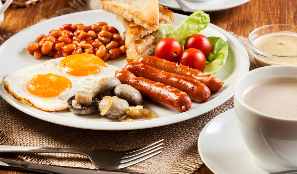 Яичница, сосиски и овощи на тарелке на завтрак