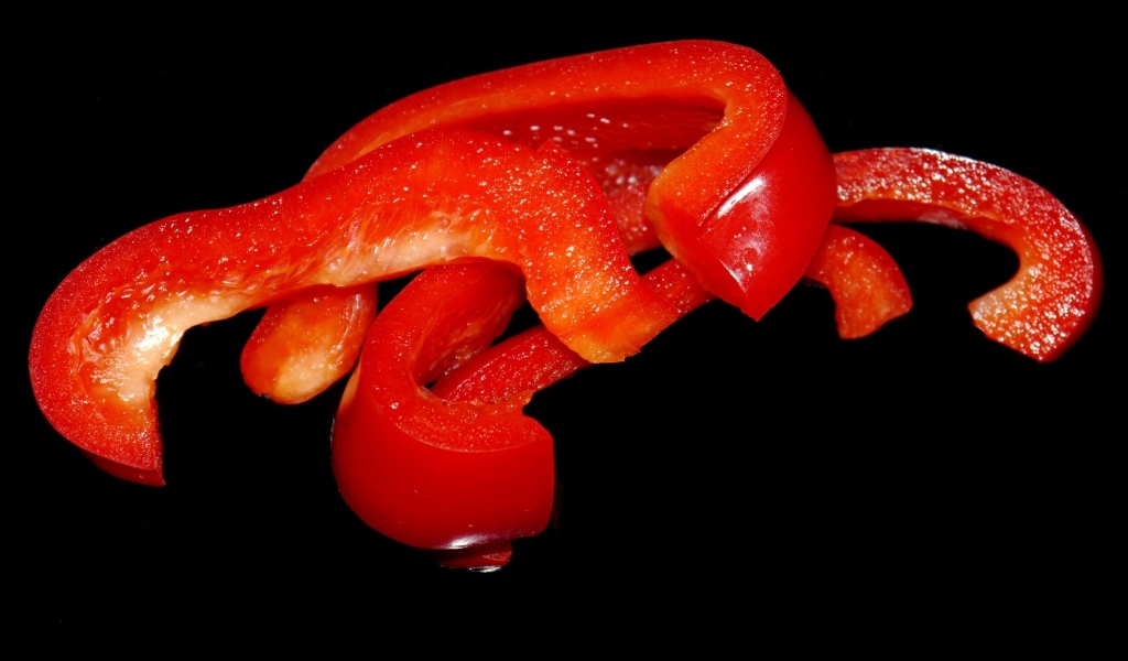 Нарезанный сладкий красный перец на черном фоне