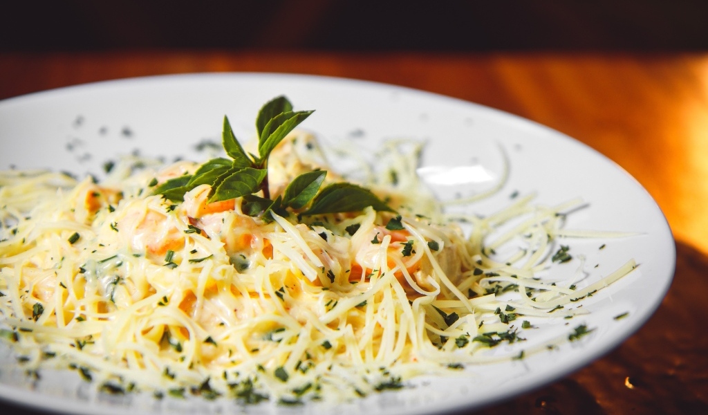 Спагетти с сыром и помидорами на белой тарелке