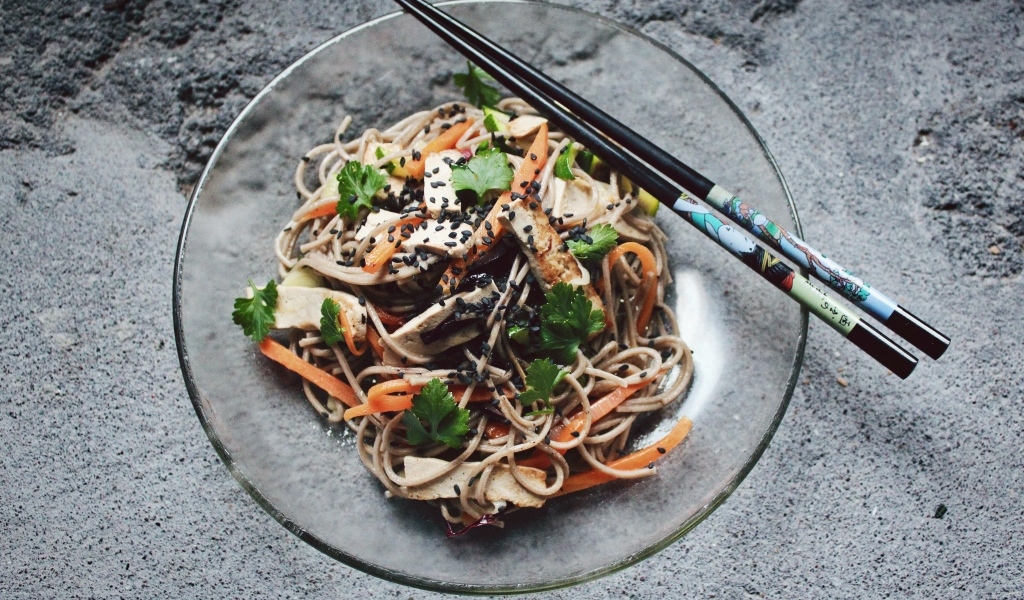 Спагетти с мясом и овощами в тарелке с китайскими палочками