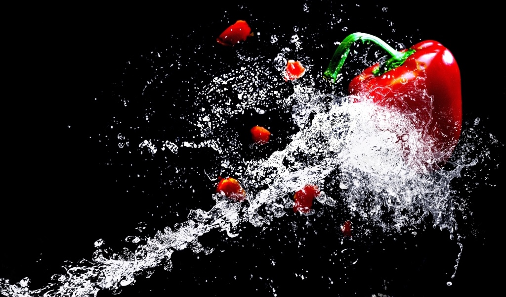 Сладкий красный перец в брызгах воды на черном фоне