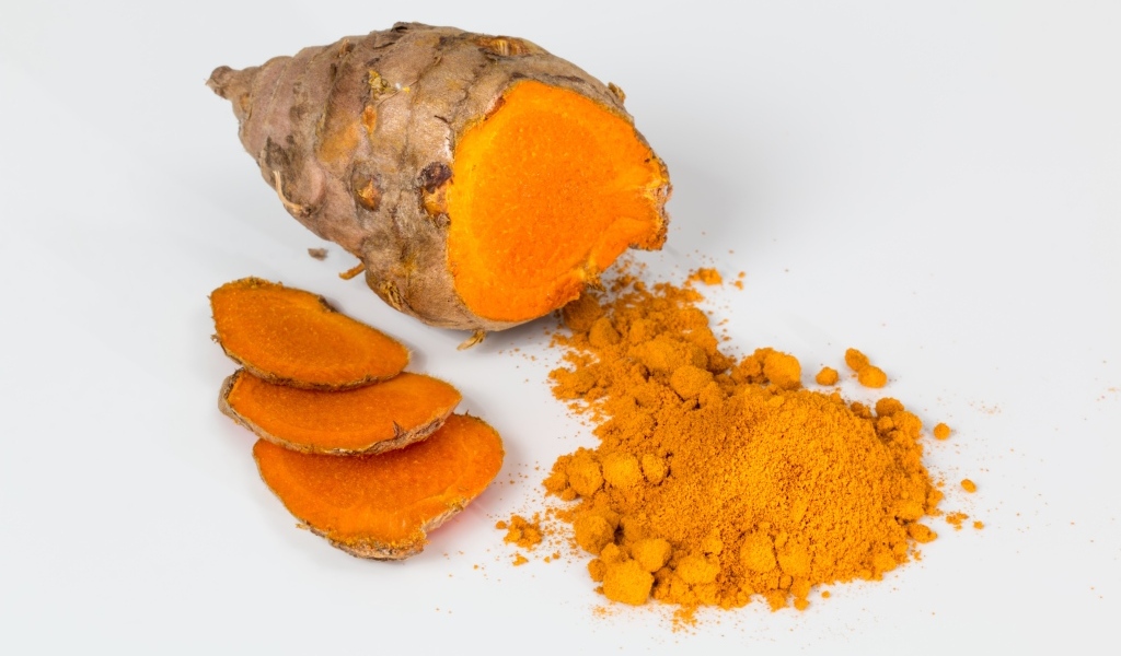 Корень куркумы с порошком на сером фоне
