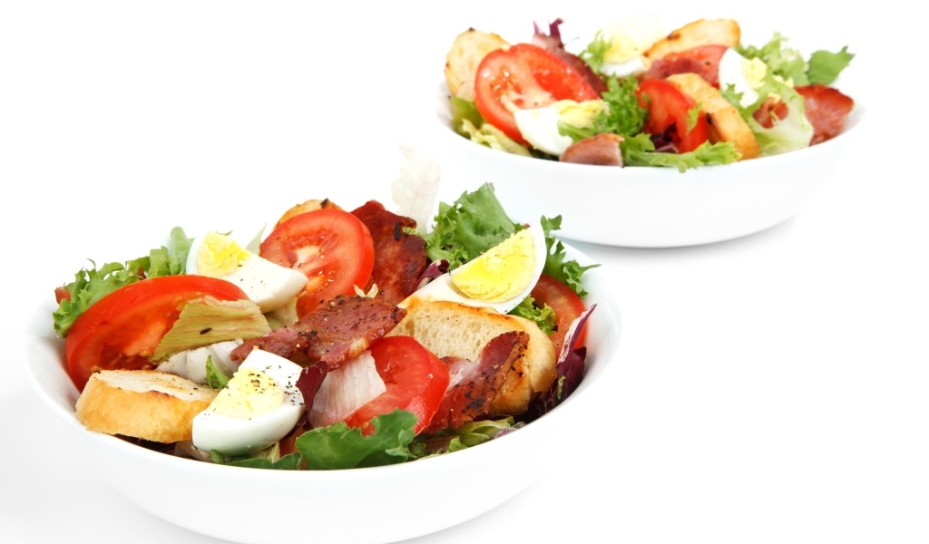 Две миски вкусного салата на белом фоне