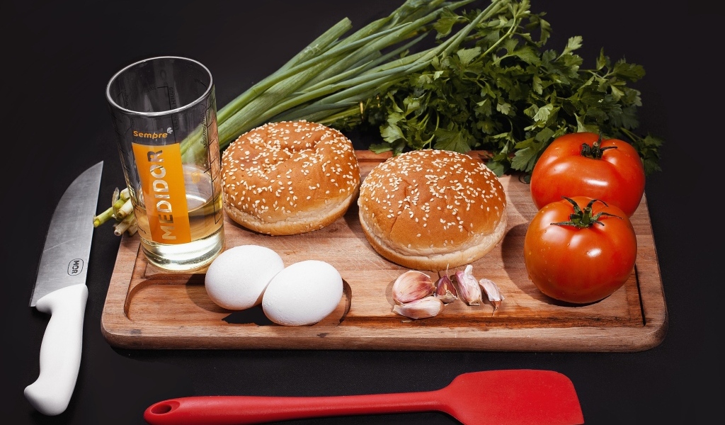 Овощи, яйца, зелень и булочки на черном фоне