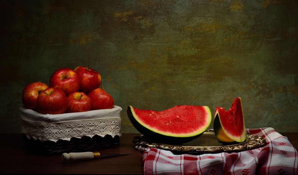 Скибки арбуза на столе с яблоками 