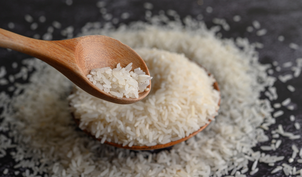 Белый рис на столе с деревянной ложкой 