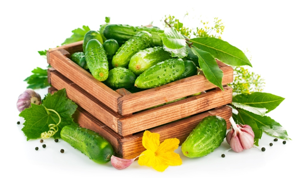 Деревянный ящик с зелеными огурцами и пряностями
