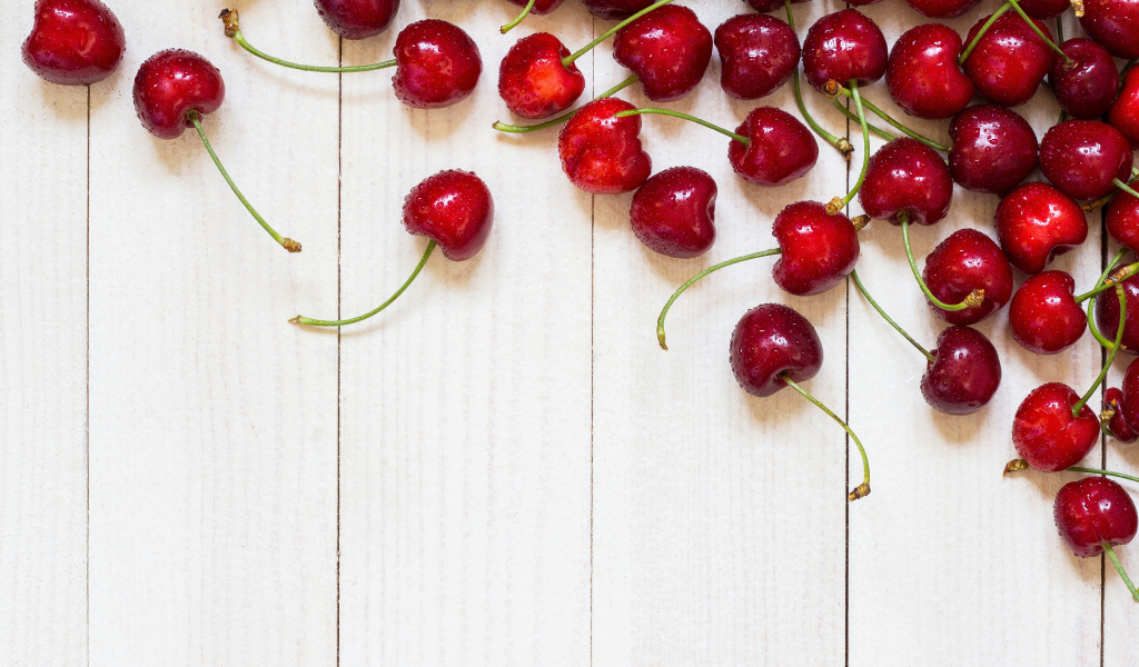 Аппетитные свежие красные ягоды черешни на белом столе