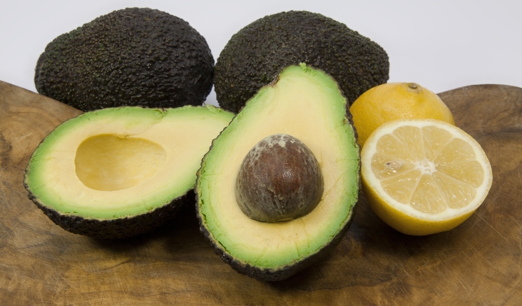 Авокадо на столе с половинками лимона