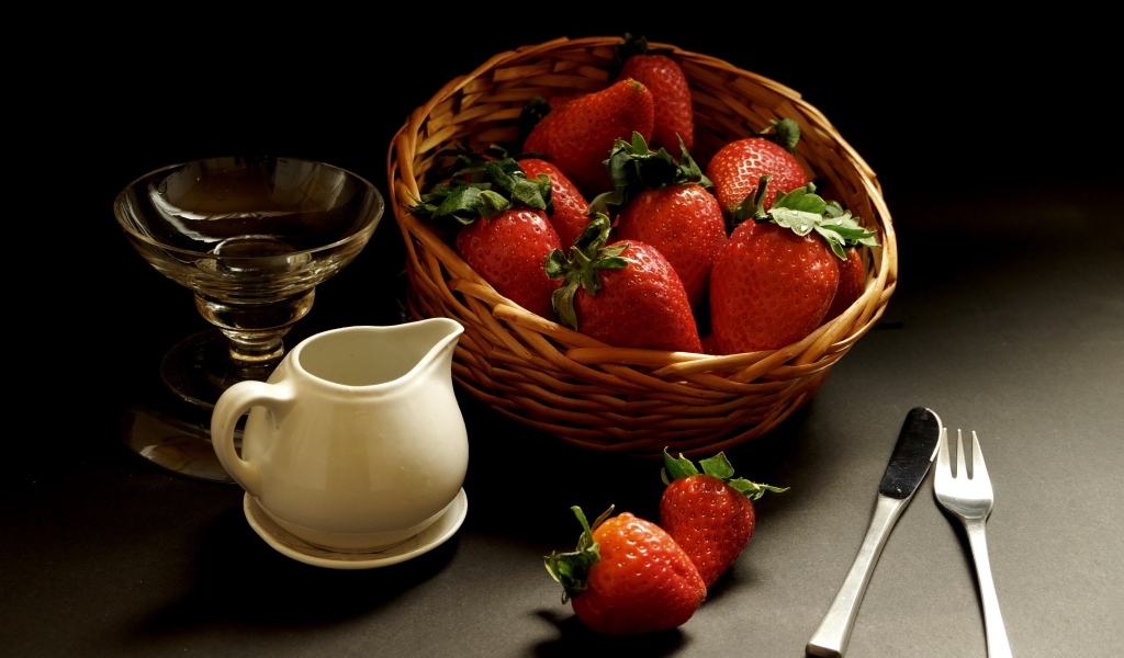 Корзина со спелой красной клубникой на столе с посудой