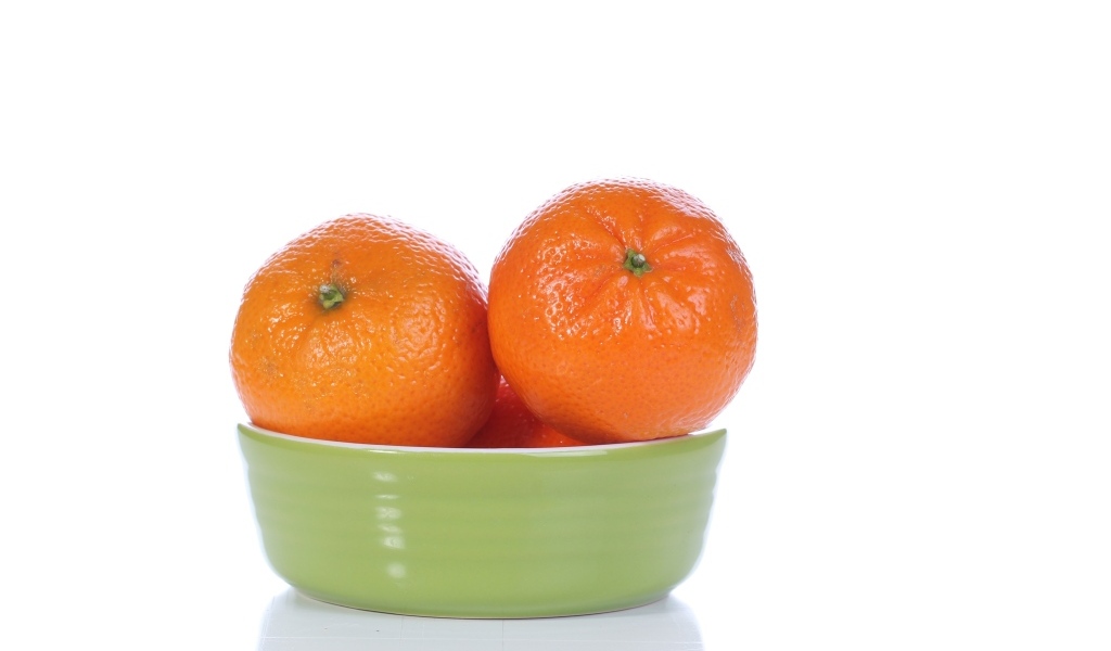 Красивые мандарины в миске на белом фоне