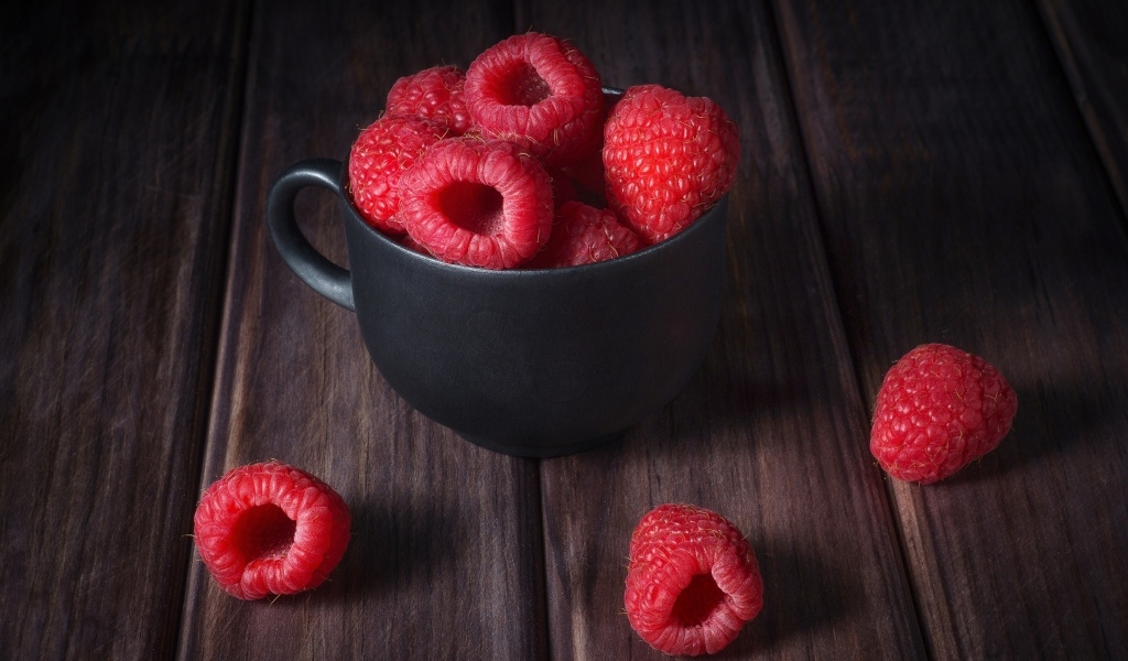 Черная чашка с красными ягодами малины