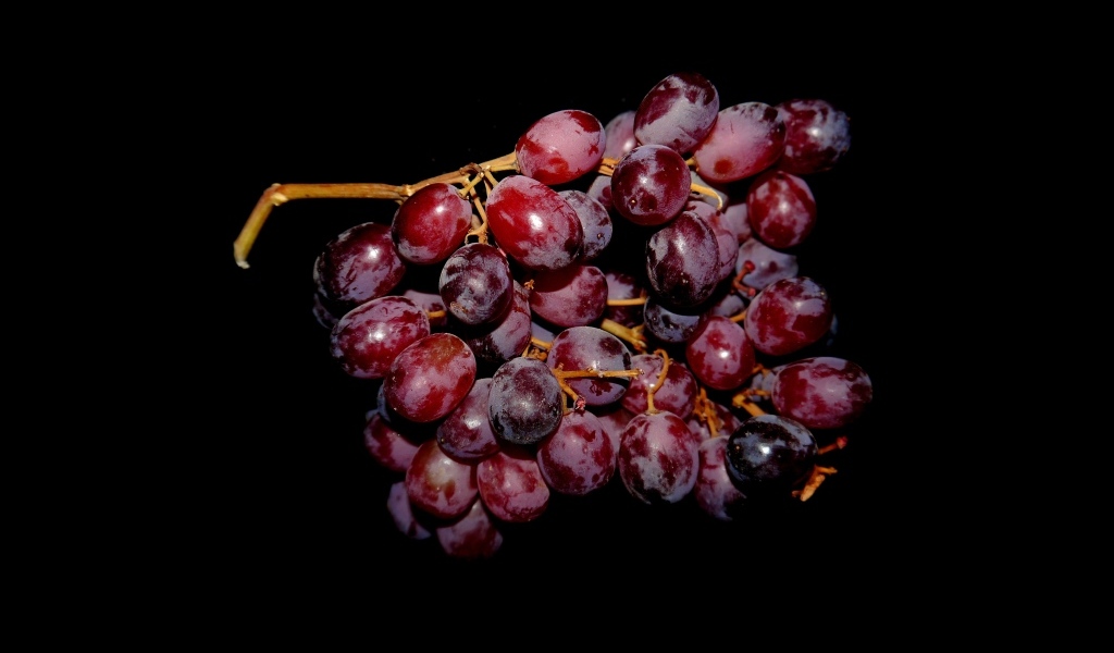Гроздь розового винограда на черном фоне