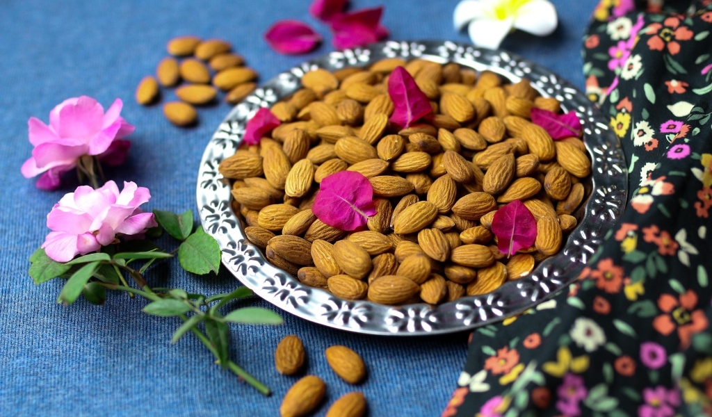 Вкусные миндальные орехи на тарелке с цветами