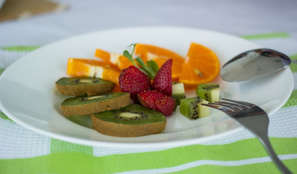 Свежие нарезанные фрукты на тарелке с вилкой