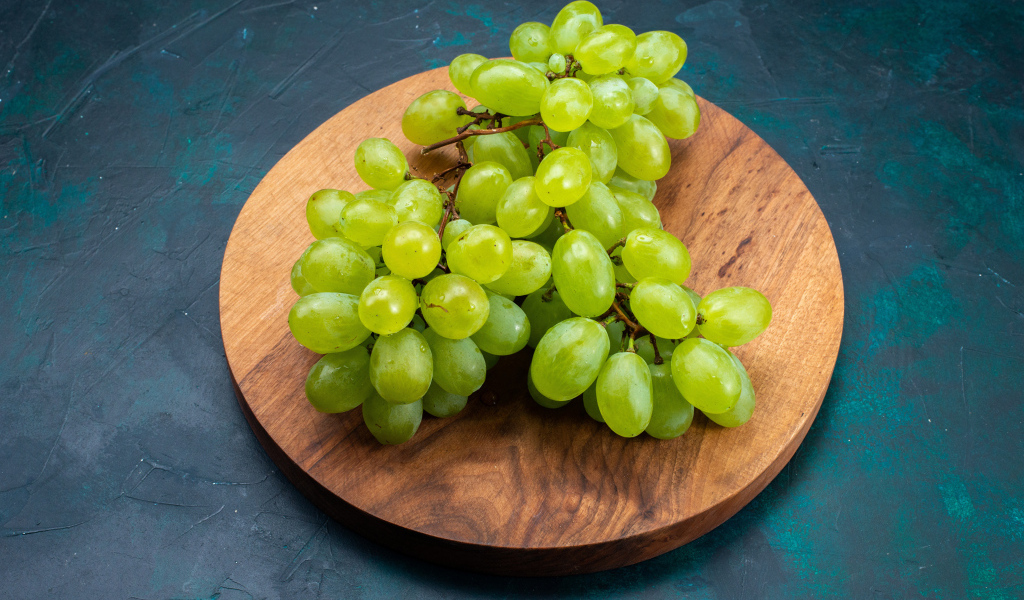 Зеленый виноград на деревянной доске