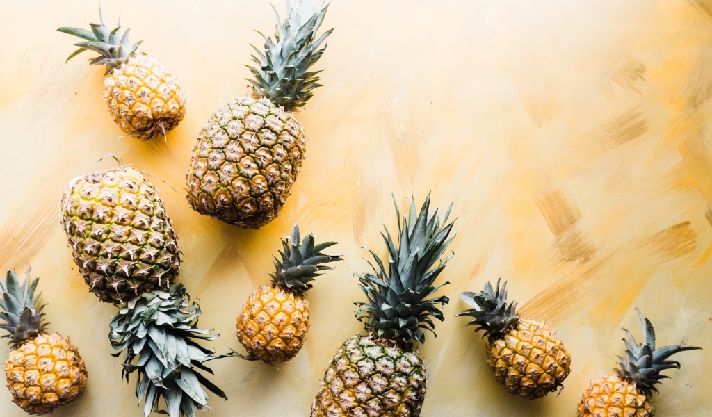 Много ананасов на желтом фоне