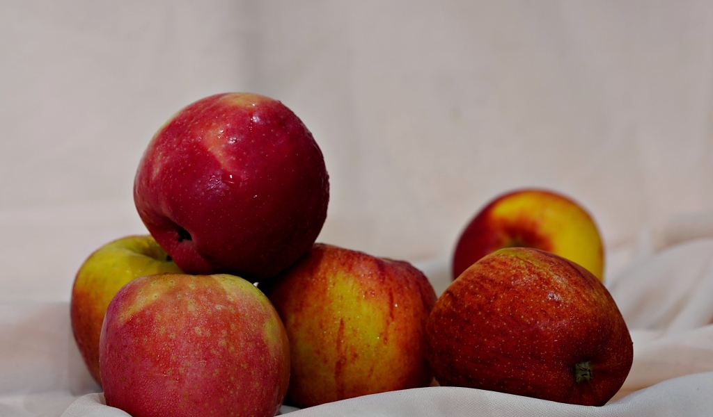 Много красных яблок с белой тканью 