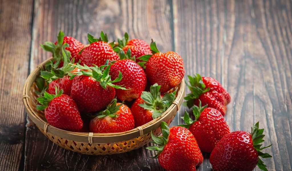 Много спелой красной клубники в деревянной посуде 