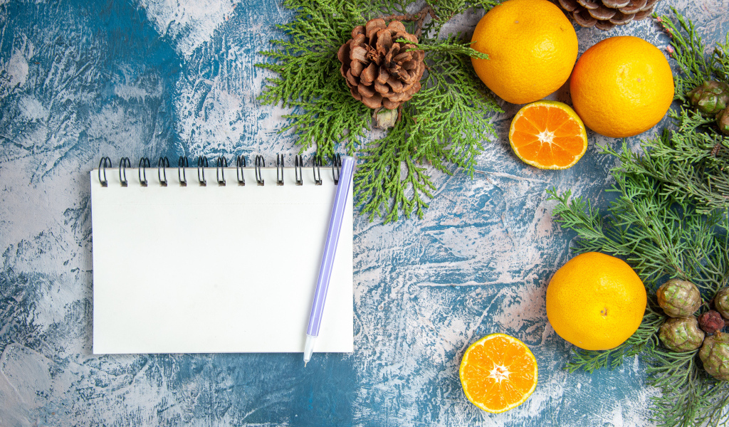 Блокнот на столе с мандаринами и ветками