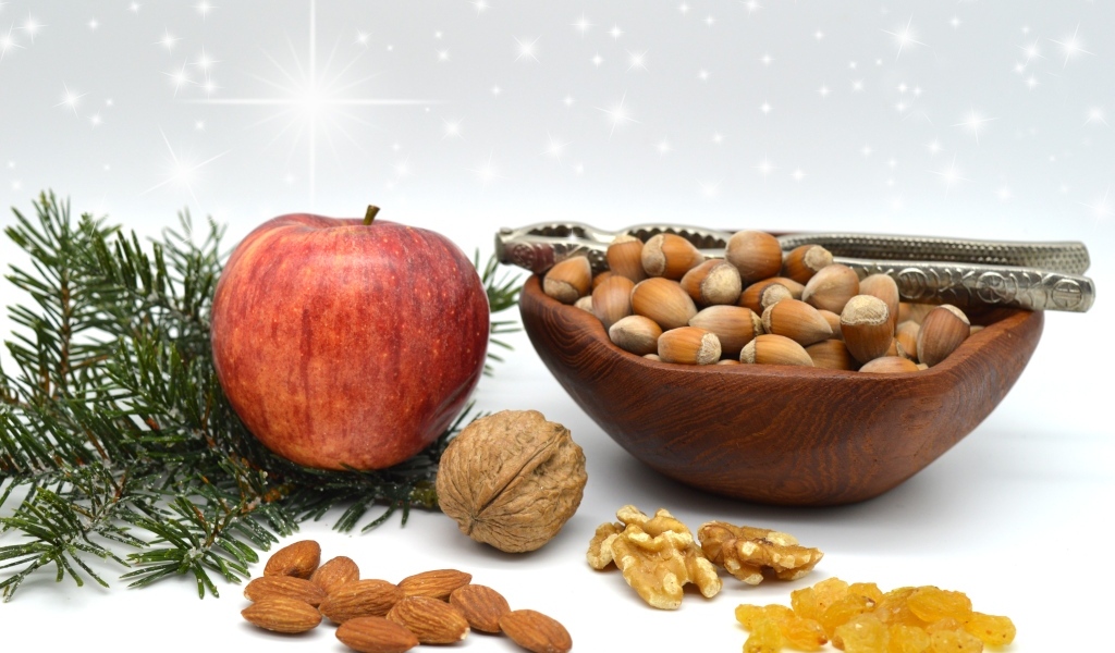 Орехи с яблоком и еловой веткой на столе