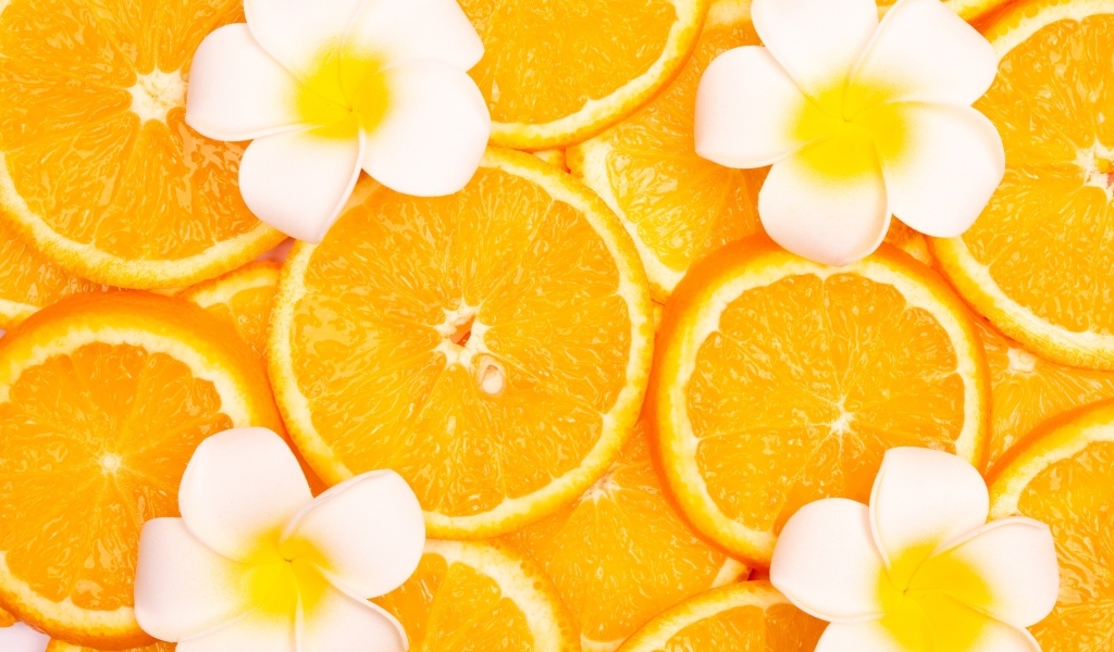 Кружочки апельсина с цветами плюмерии крупным планом