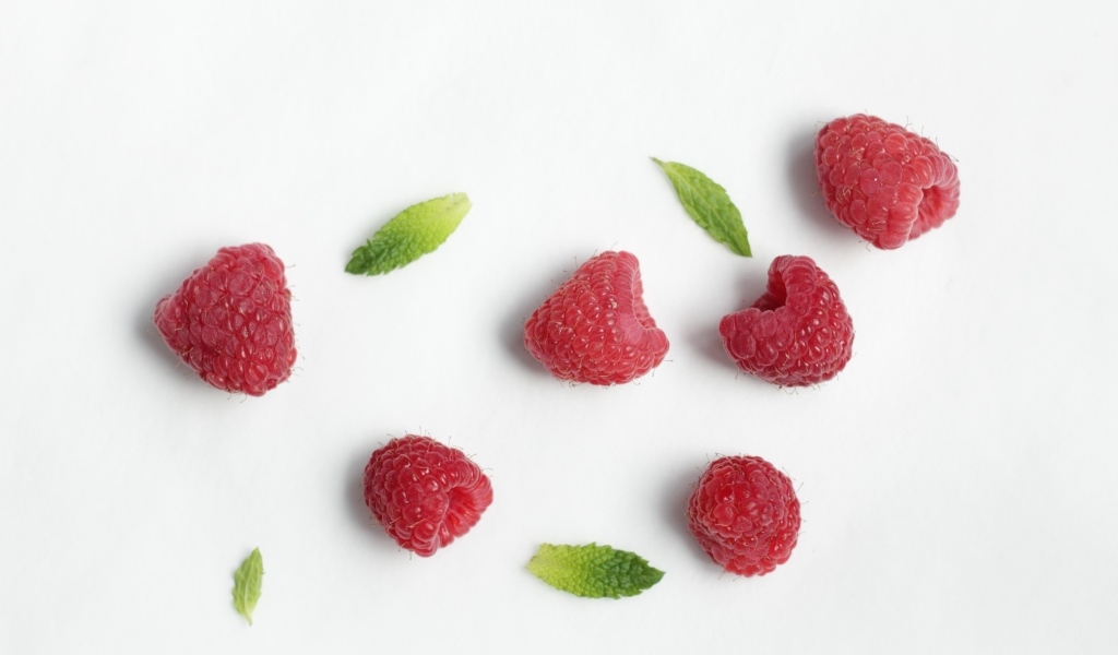 Красная малина с зелеными листьями на белом фоне