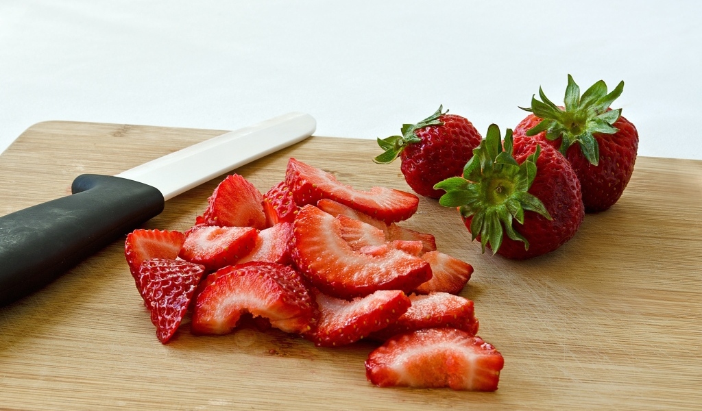 Красная клубника нарезана на деревянной доске