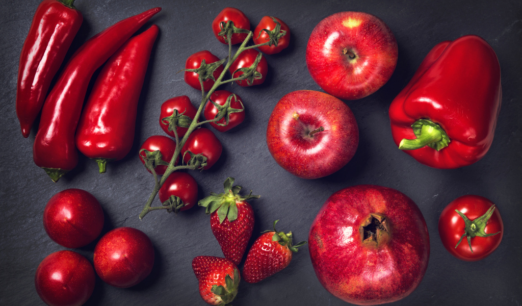 Красные овощи и фрукты на сером столе