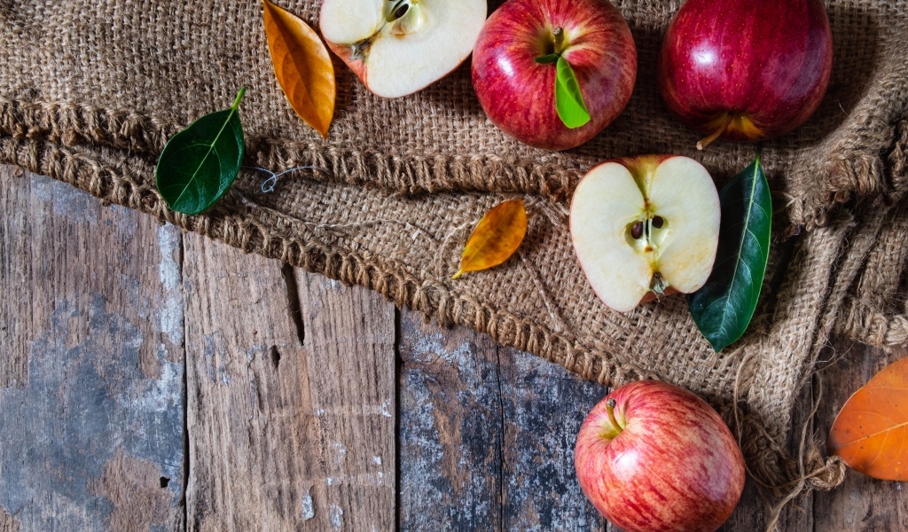 Спелые красные яблоки на столе с мешком