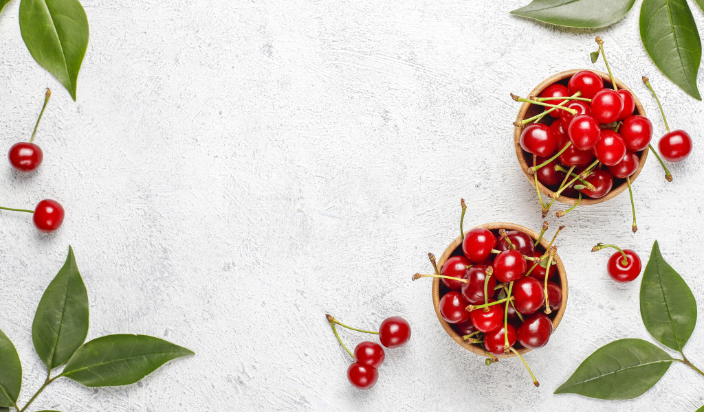 Спелая красная вишня с зелеными листьями на столе
