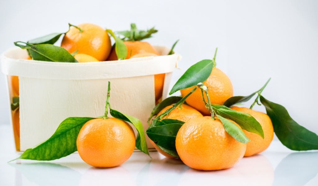 Спелые сладкие мандарины с корзиной на столе