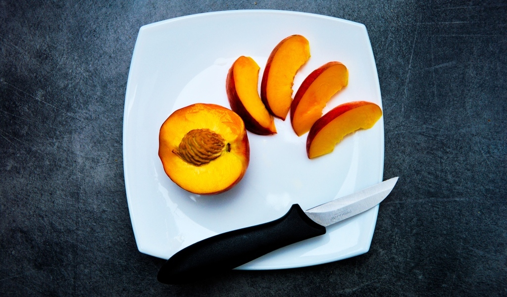 Нарезанный персик на белой тарелке