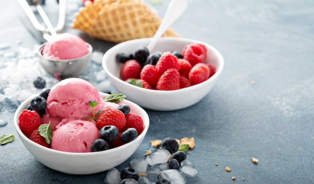 Сладкие ягоды с шариками мороженого на столе