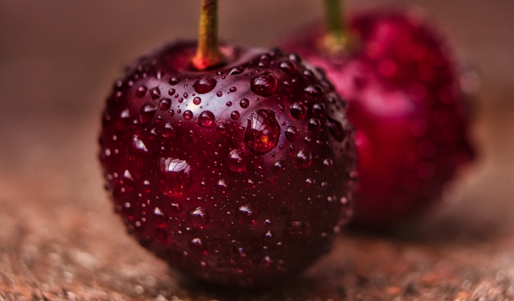 Две красные ягоды черешни в каплях воды