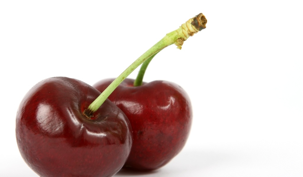 Две красные ягоды черешни на белом фоне