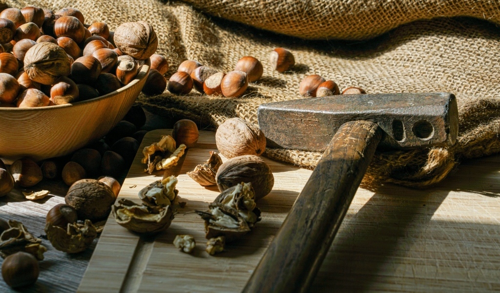 Грецкие орехи и фундук на столе с молотком