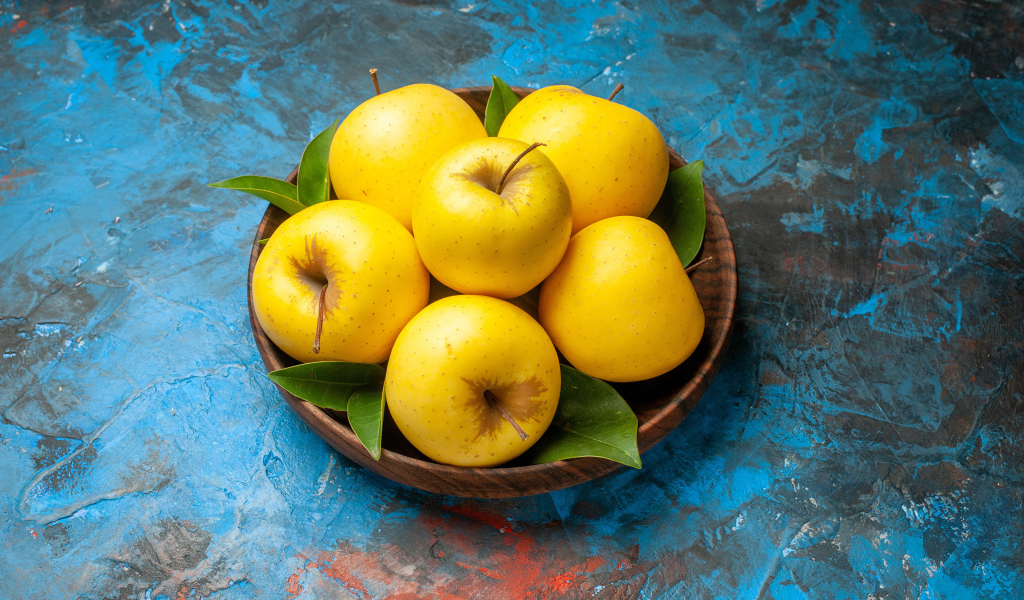 Деревянная тарелка с яблоками на столе