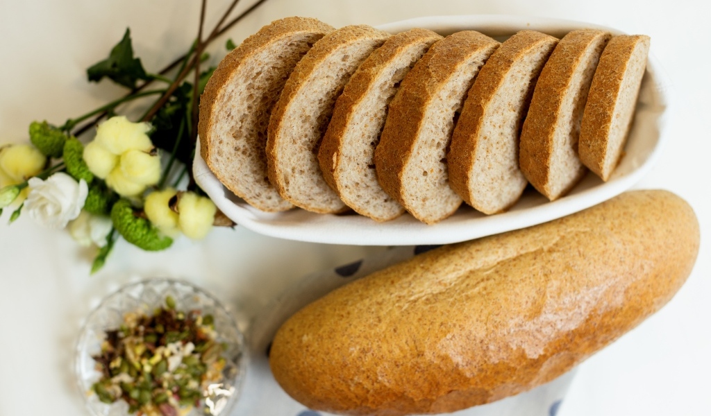 Батон нарезанный на столе с цветами